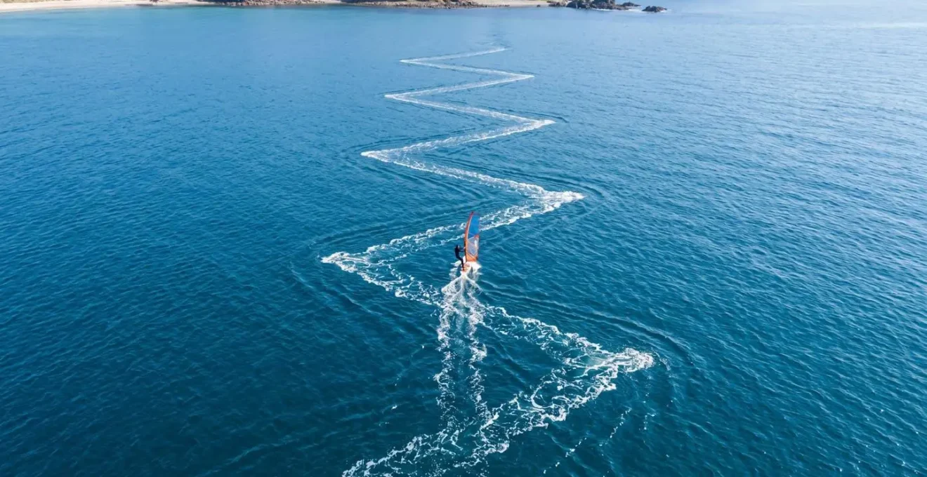 Vista aerea di un windsurfista che esegue la bolina a zig-zag per risalire il vento
